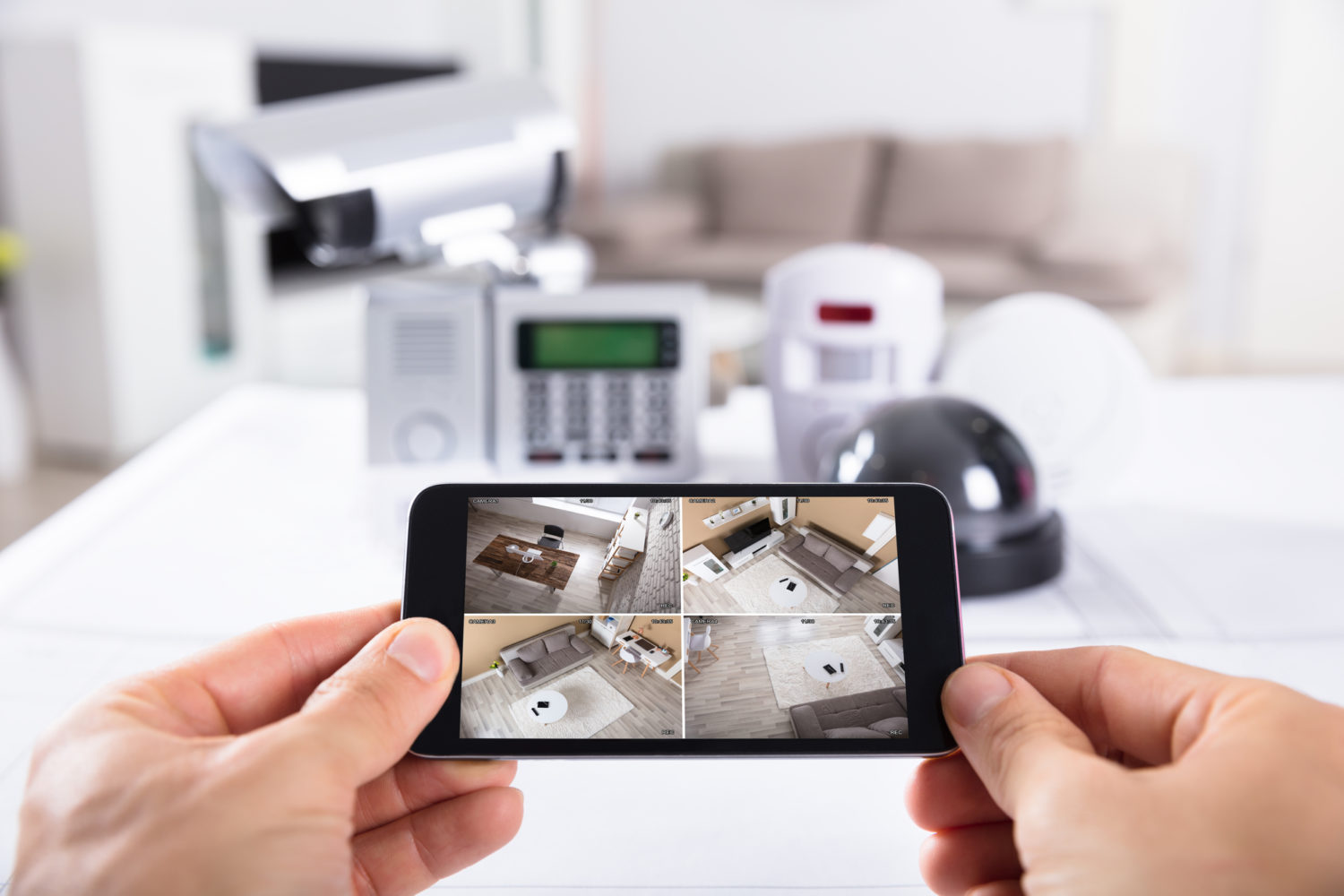 Close-up Of A Person's Hand Holding Mobile Phone With CCTV Camera Footage On Screen